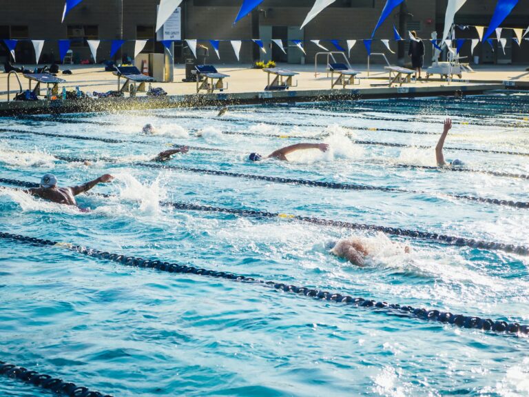 Athletes practicing in a sunlit outdoor swimming pool, showcasing dynamic swimming strokes.